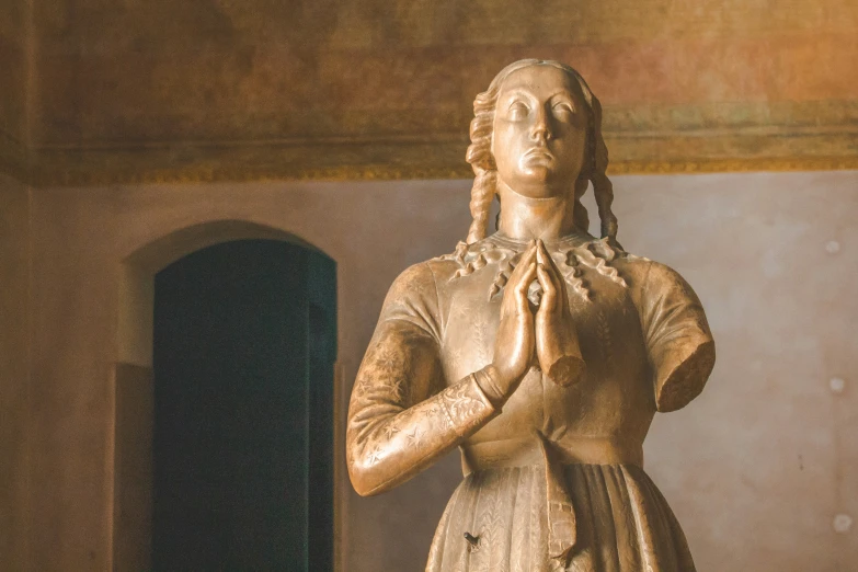 a statue of a woman praying next to a building