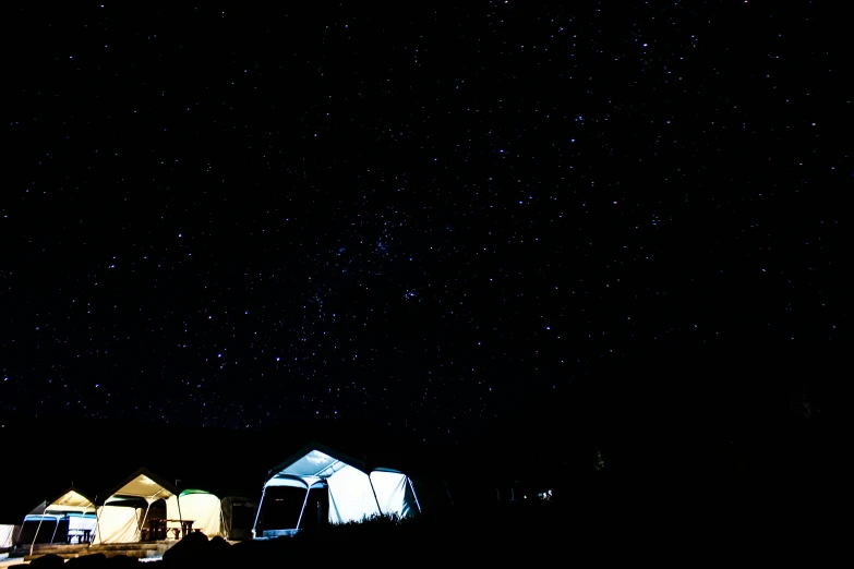 a dark, gloomy night with stars above a few tents