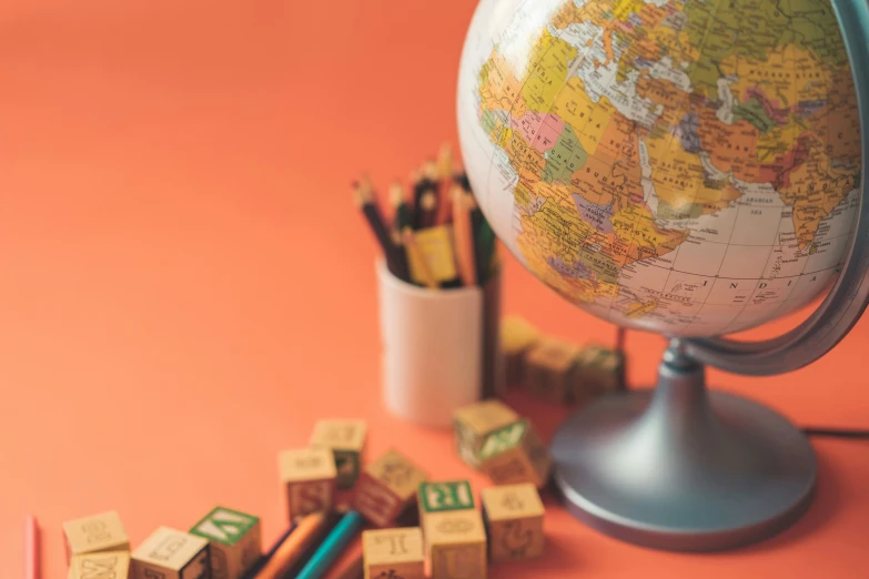 a group of wooden cubes next to a globe and several colored pencils