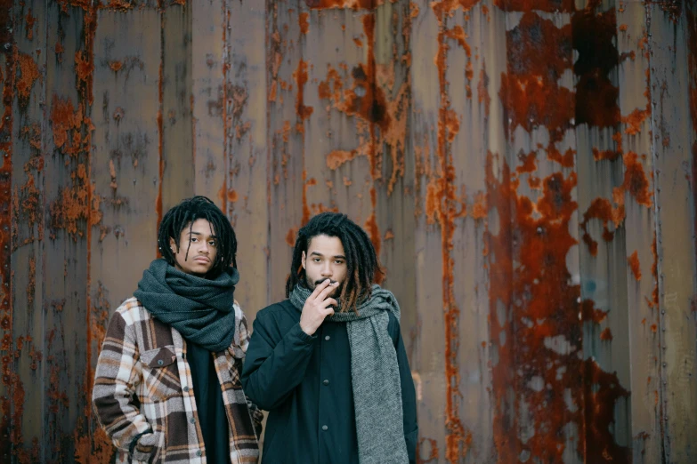 two men are standing together by some rusted fence