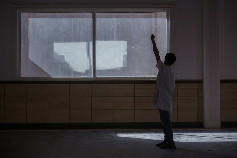 a man in dark room waving at the sun