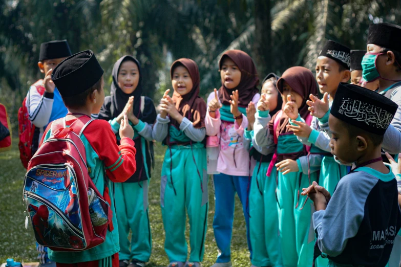 many children with school bags and back packs and one is giving the peace sign