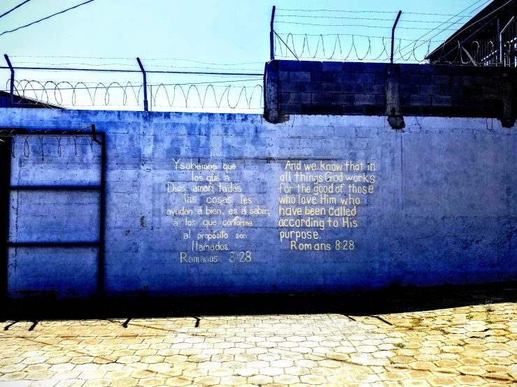 a wall with writings is in front of razor wire