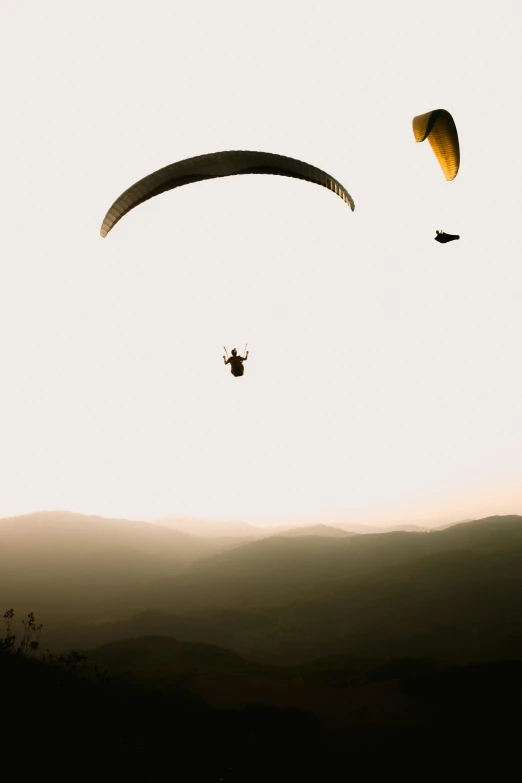 two people in the air over mountains on kites