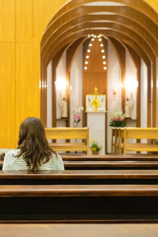 back view of woman seated in front of wooden church pews