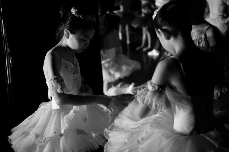 two s dressed in dresses looking at a mirror