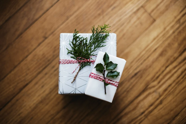 two wrapped christmas presents wrapped in white paper