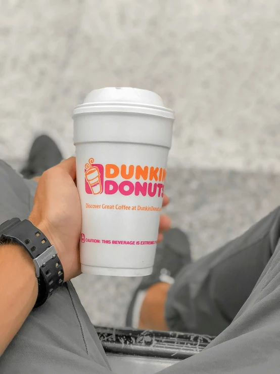 person sitting on floor holding coffee cup in hand