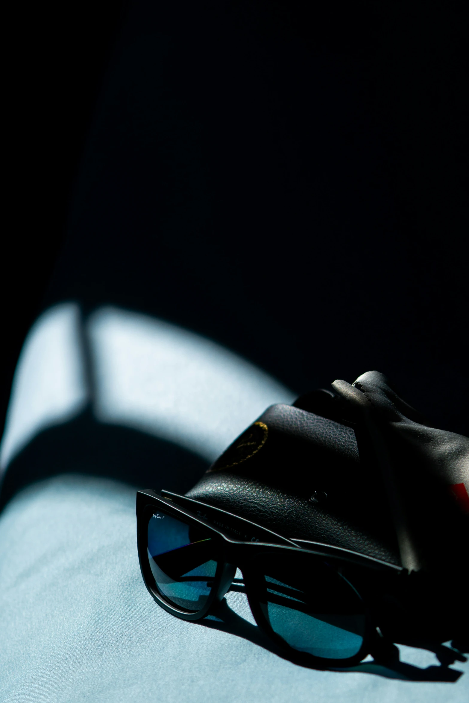 a pair of sunglasses sits next to an open leather purse