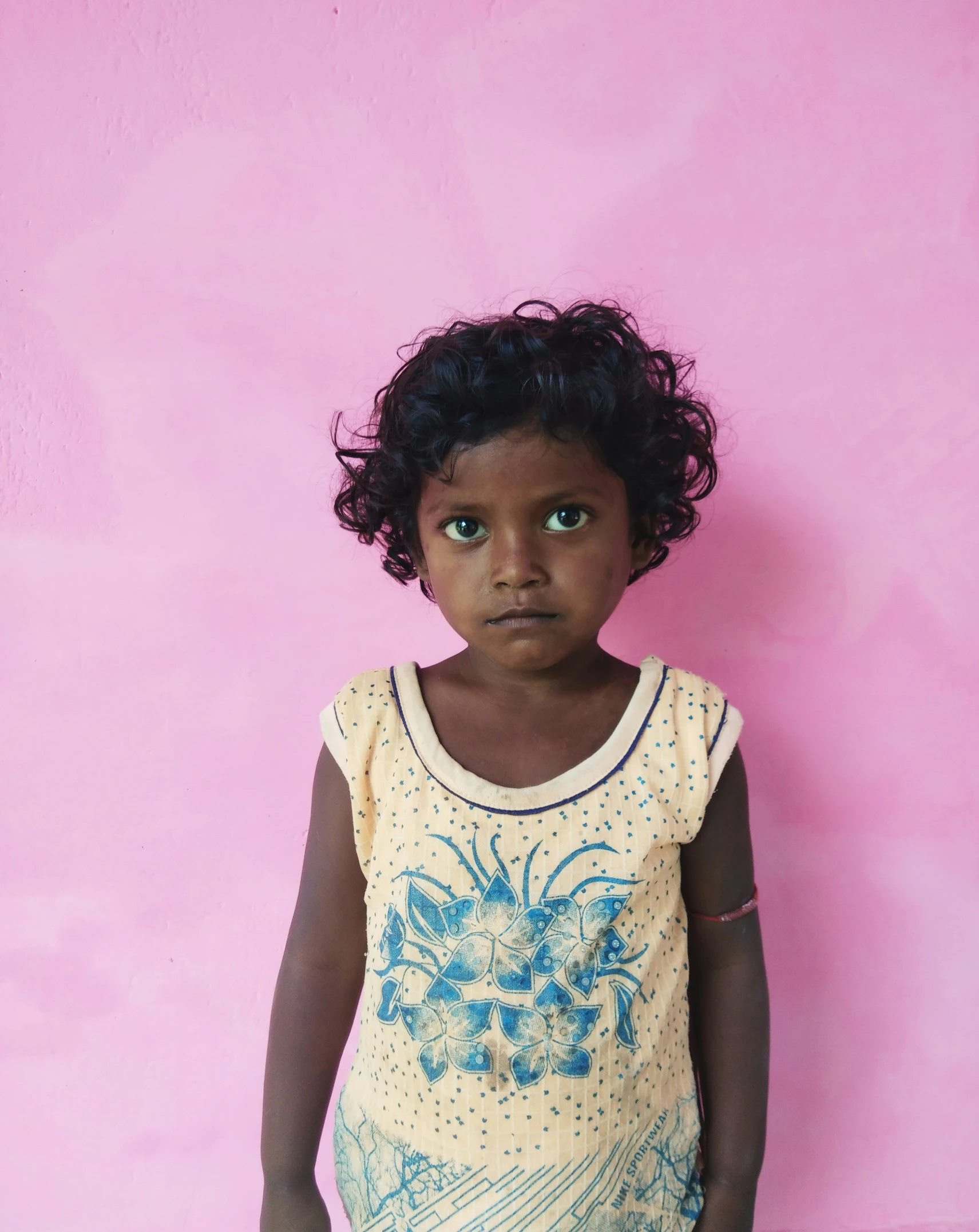 a child standing next to a pink wall