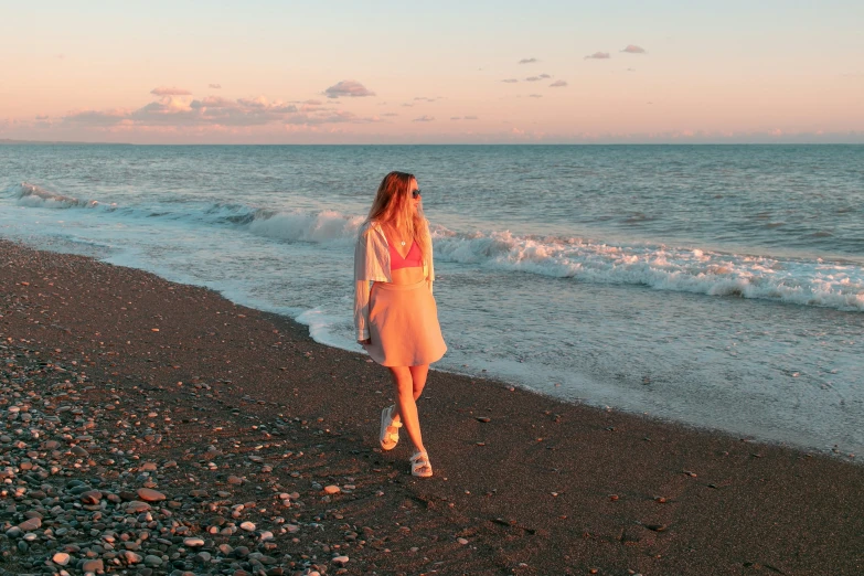 the woman is standing on the beach looking at the ocean