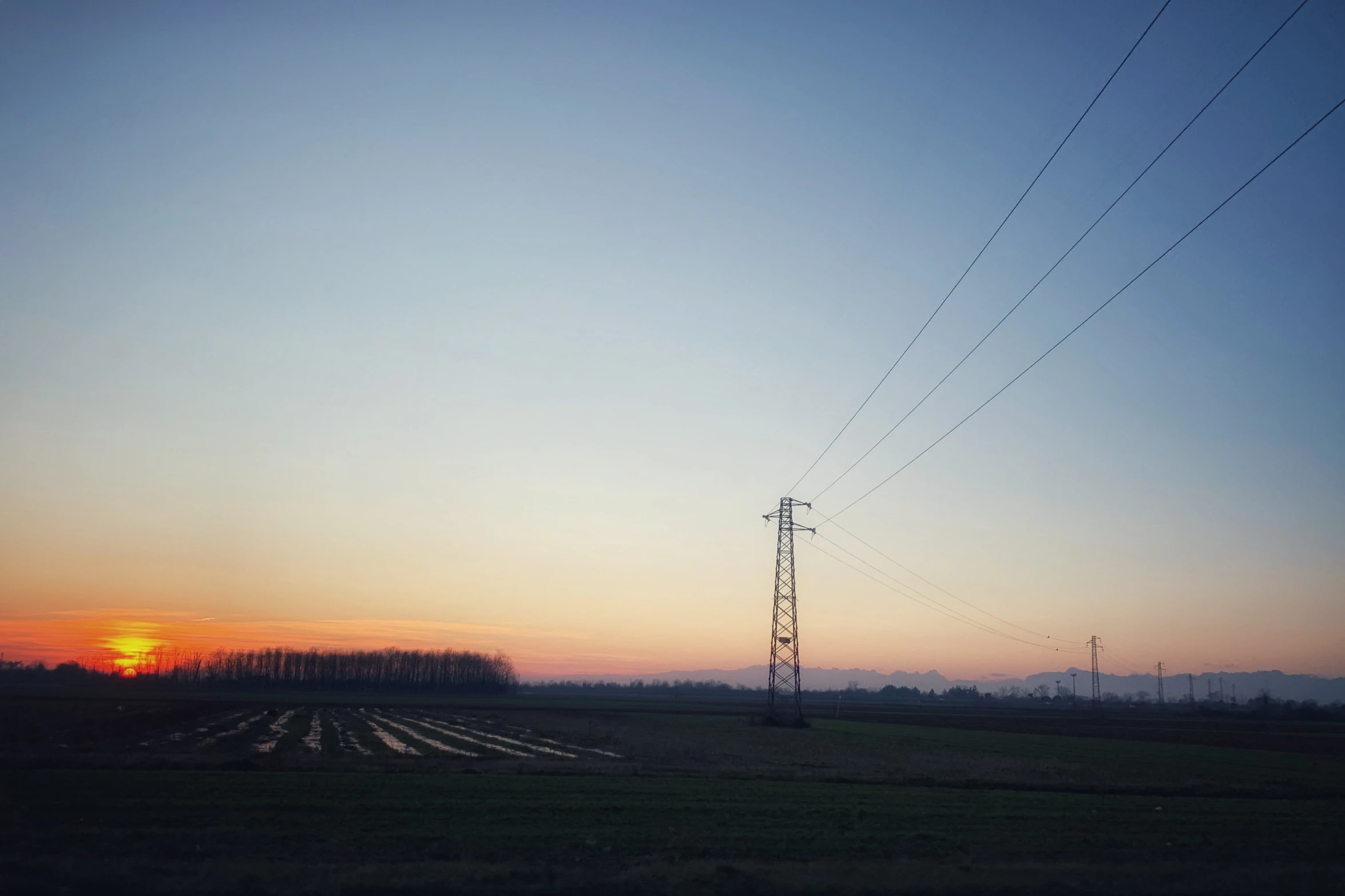 sunset behind electric towers and utility poles