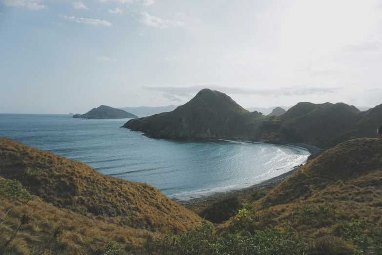 two people standing on a hill by the ocean