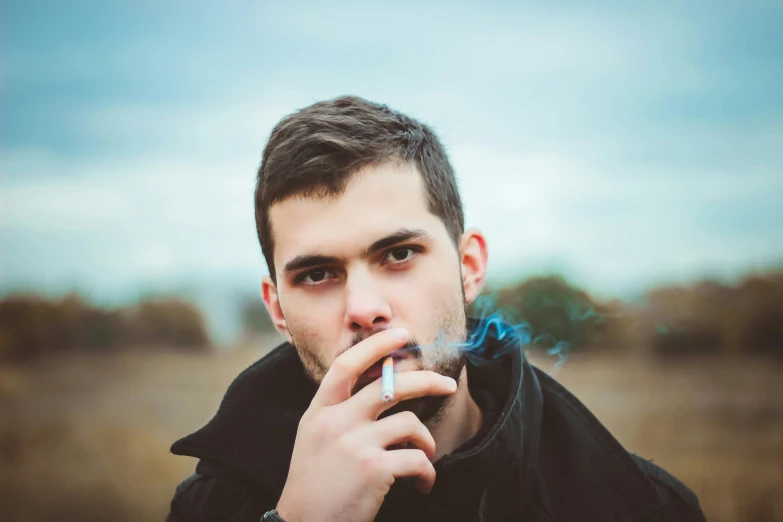 a man is smoking a cigarette in a field