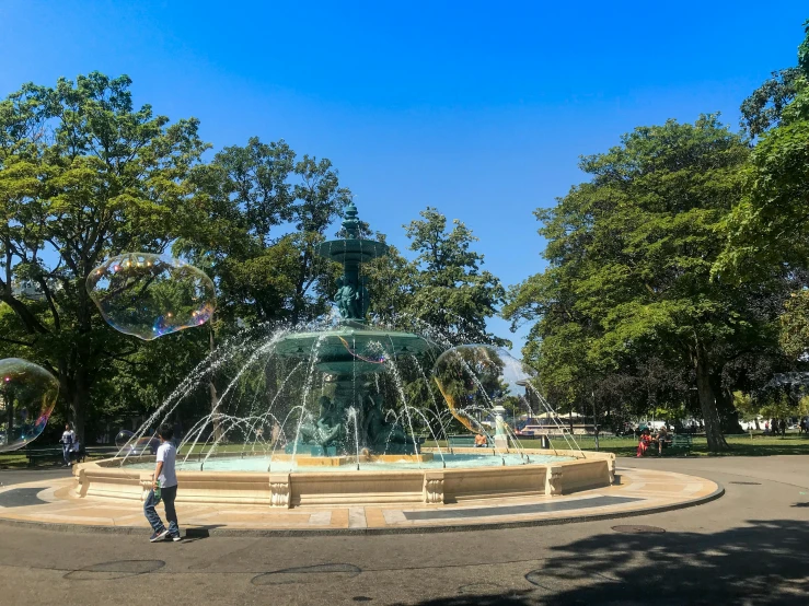 a water fountain in a park with people walking by