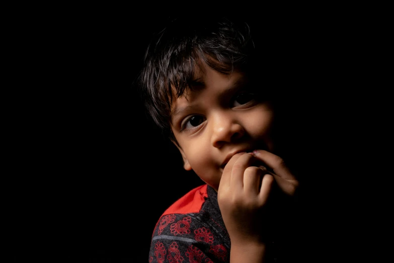 a little boy is holding his finger in his mouth