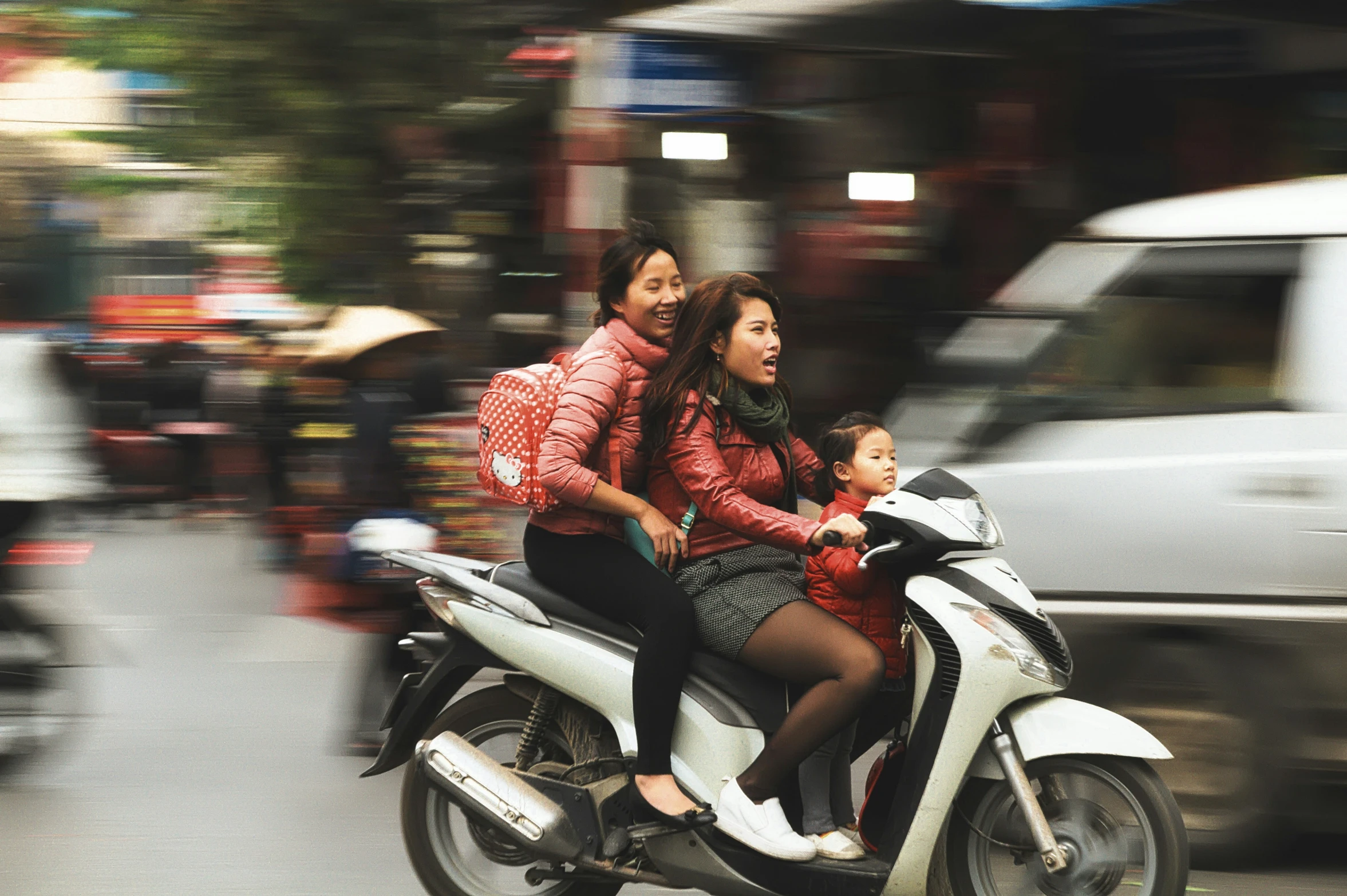 a woman with a baby riding on top of a moped