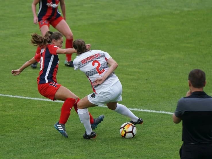 several women on two teams are playing soccer in the field