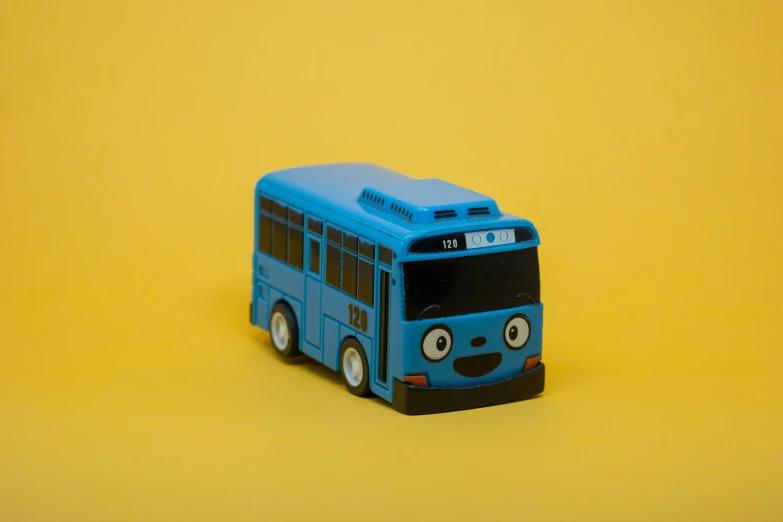 a blue toy bus sitting on a yellow background