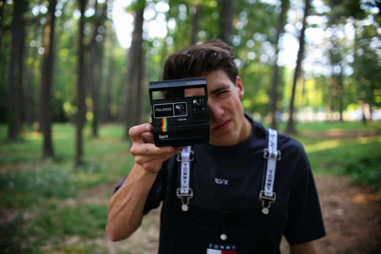 a man holding up a polaroid camera while he takes a picture