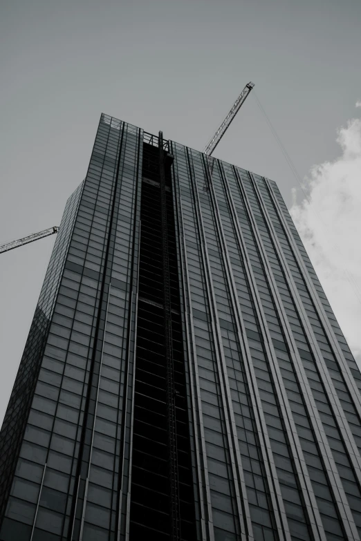 a tall building with cranes next to it