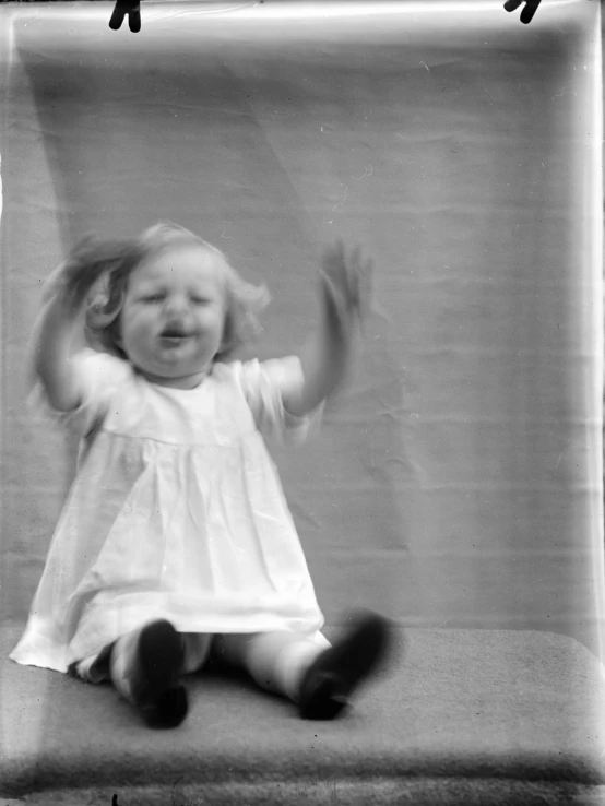 a girl with her hands up sitting in front of a wall