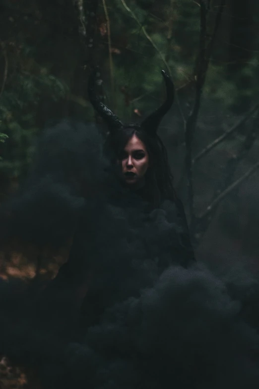 a woman standing in front of trees wearing horned horns