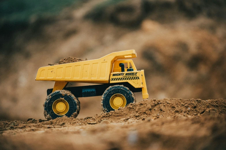 a yellow toy dump truck parked in a field