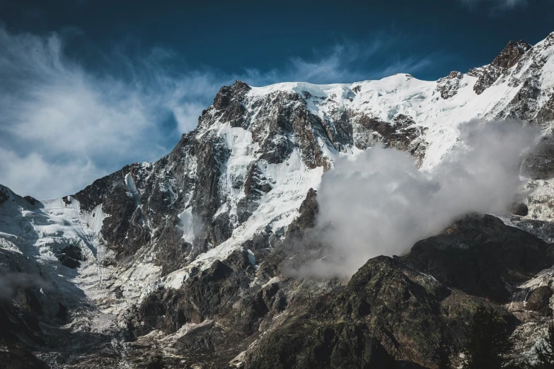 a white - capped mountain is covered in cloud