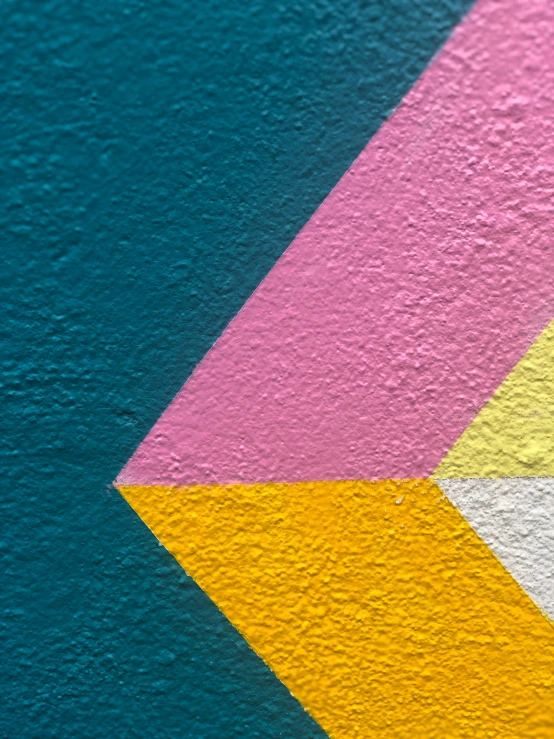 the bottom corner of a blue building wall with yellow and pink lines