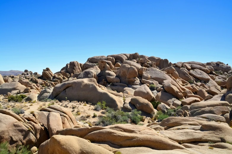 a hill with large boulders in a field of grass and dirt