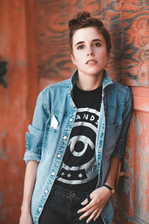 a young lady leaning against an old orange wall