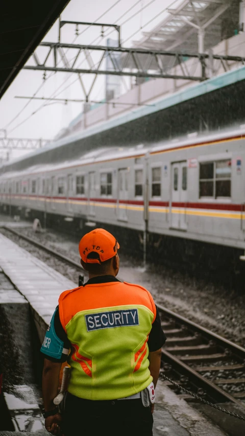 a train conductor watching a subway go by on the side of the track