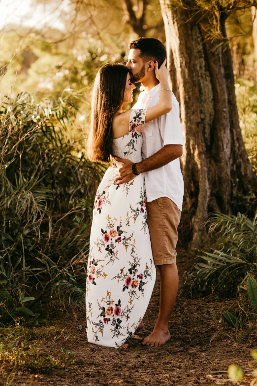 the young couple is kissing in front of the trees