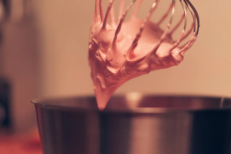 a pink hand mixer with a red wire inside