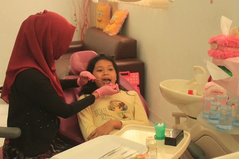 a child in a highchair being put in his teeth