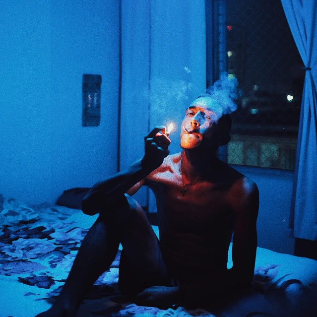 a person is laying in bed and smoking a cigarette