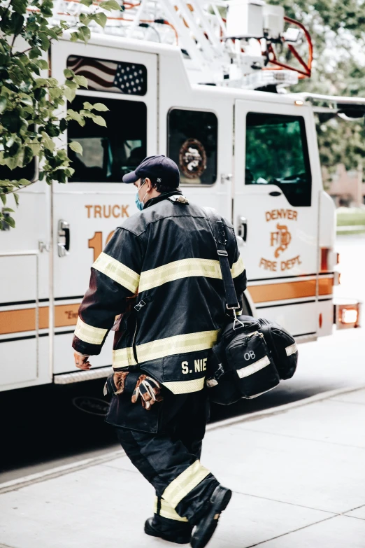 the fire fighter is walking down the street carrying his luggage