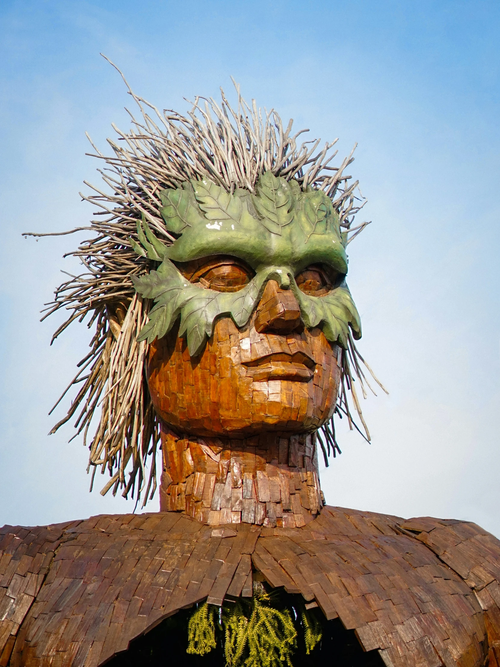a wooden carving sculpture of a man with spiked hair