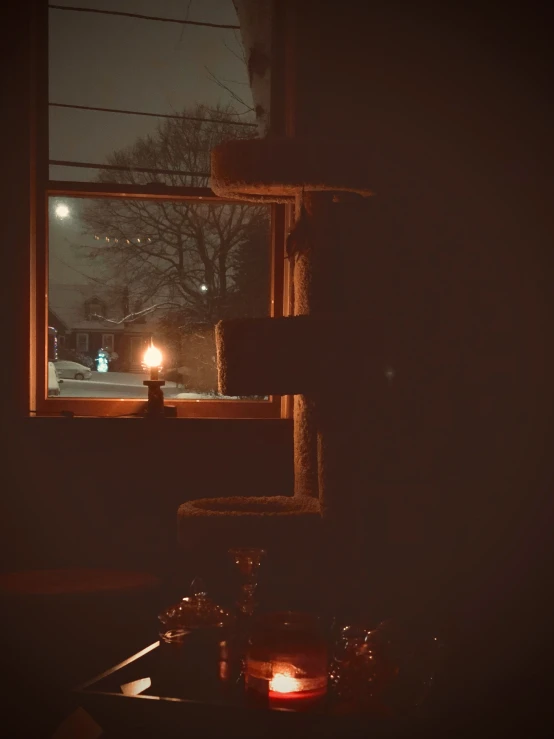 a lighted candle sitting in front of a window