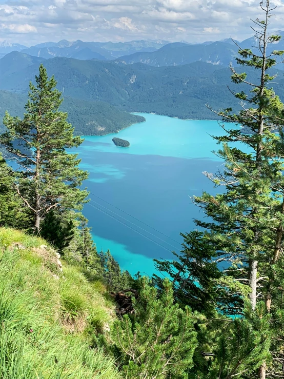 two young men are climbing up on a hill overlooking the blue lake