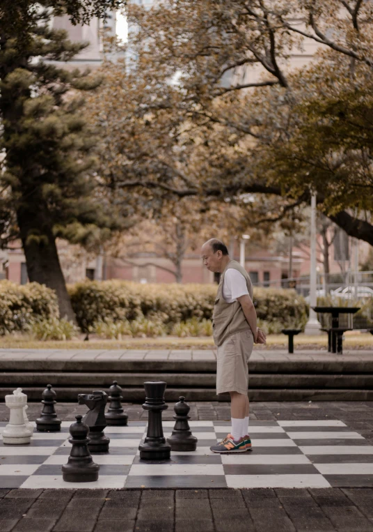 the man standing in front of the chess board is making his way towards the end of the board