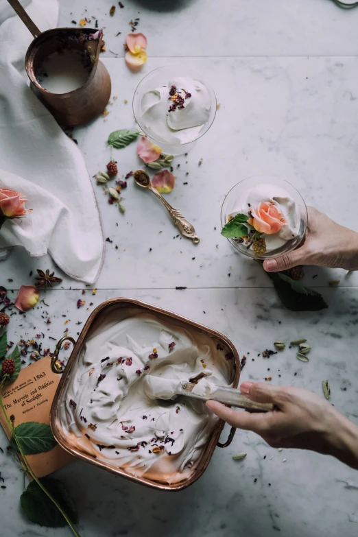 hands hold spoons to dip a small bowl of whipped cream