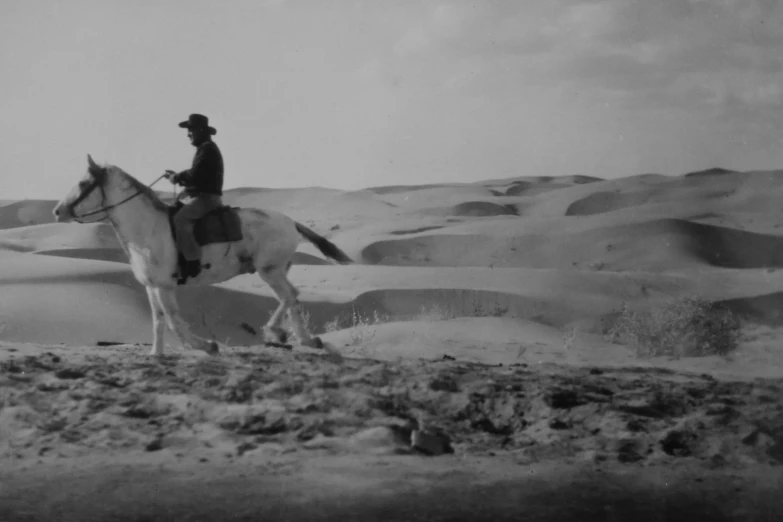 a man on a horse riding in a barren desert landscape