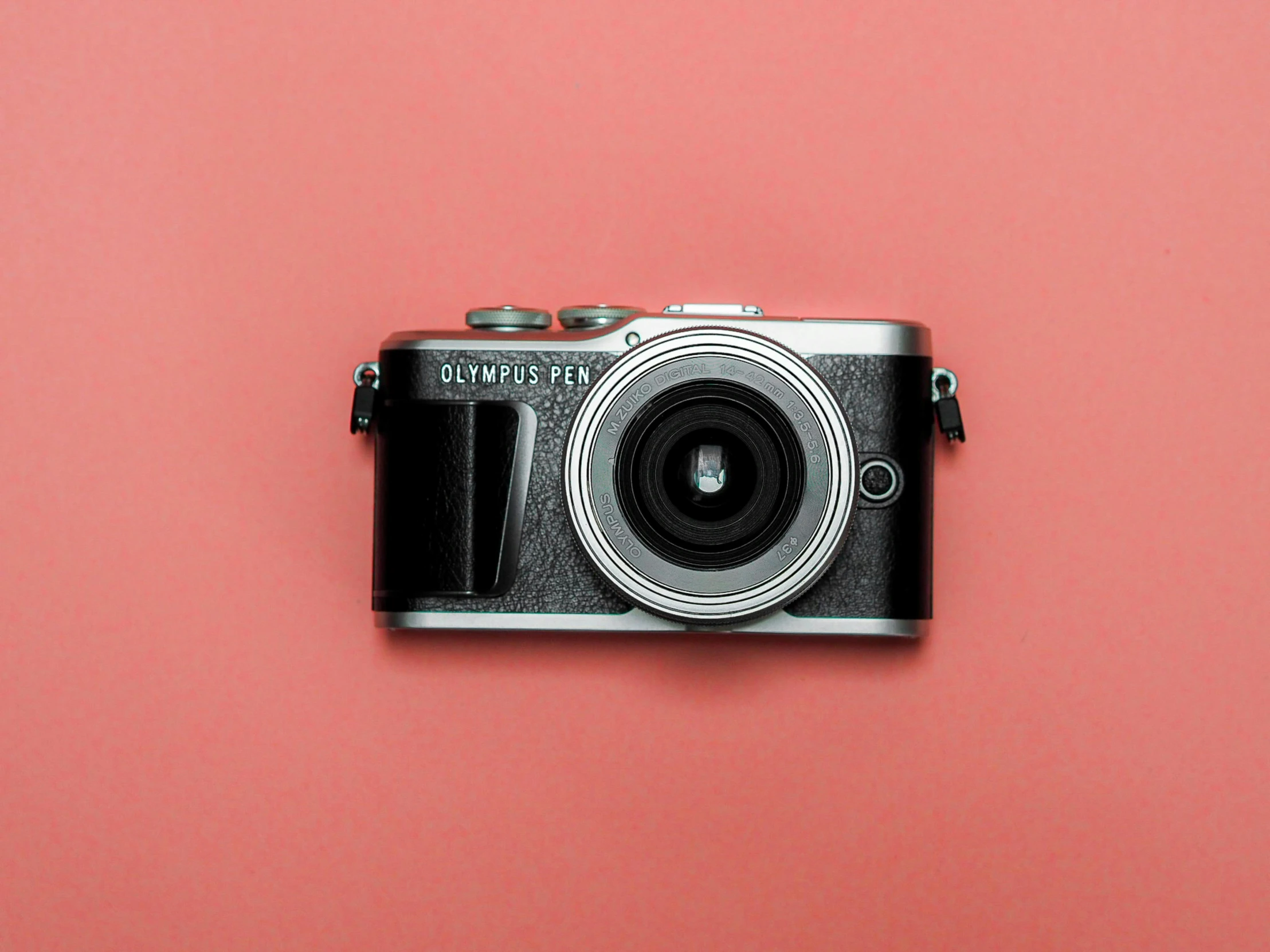 a vintage camera on a pink surface with a white background