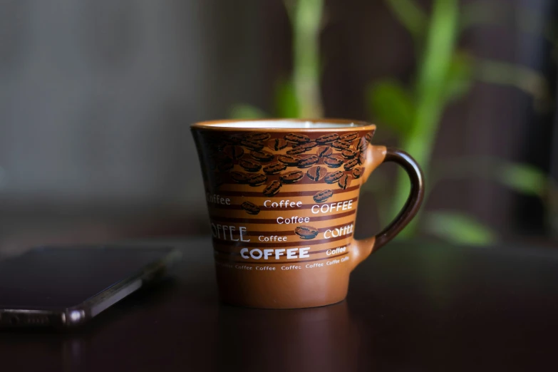 coffee cup sitting on table near cell phone