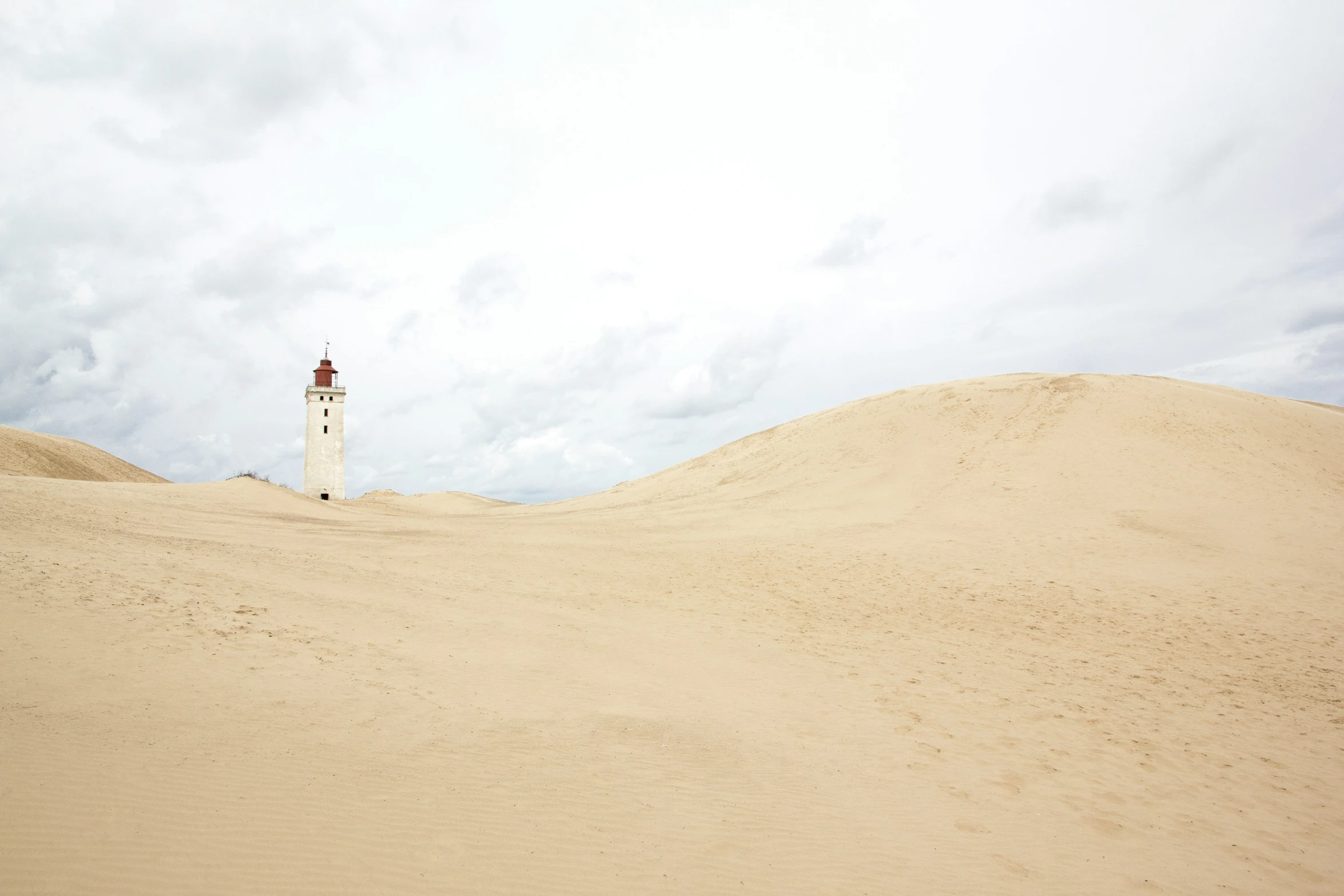 a tall light tower in the sand near a sky