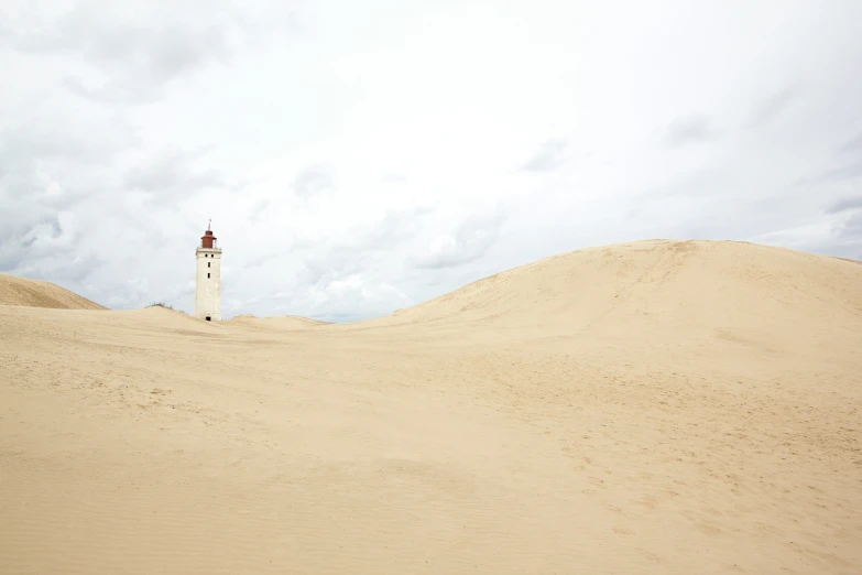 a tall light tower in the sand near a sky