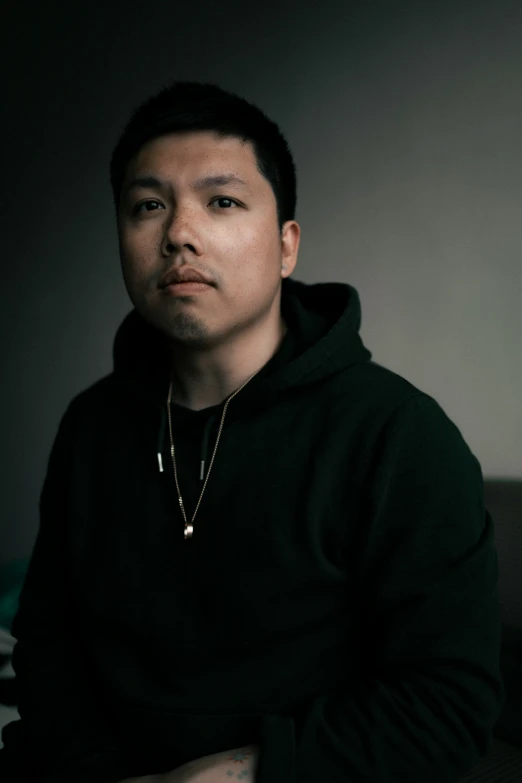 a young man posing for a po, with a hoodie on