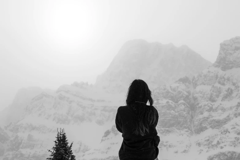 a woman standing in the snow next to a mountain